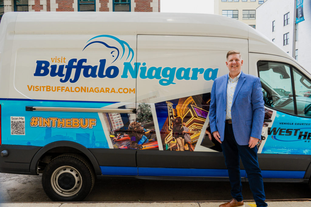 President & CEO of Visit Buffalo Niagara, Patrick Kaler poses in front of their branded van